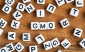 Small white and black bead cubes on wooden board, letters in middle spell GMO - genetically modified food concept Royalty Free Stock Photo