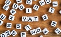 Small white and black bead cubes on wooden board, letters in middle spell VAT - Value Added Tax Royalty Free Stock Photo