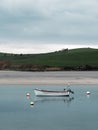 A small white boat at anchor. Calm water surface. Picturesque hills on the shore of the bay Royalty Free Stock Photo