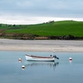 A small white boat at anchor. Calm water surface. Picturesque hills on the shore of the bay. The sandy shore Royalty Free Stock Photo