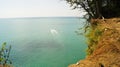 Small white boat sailing from the coast of the azure sea waters to the horizon.