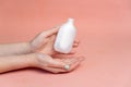 Small white bottle in women`s hands, hand cream, face cream, women`s cosmetics