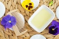 Small white bowl with cosmetic massage, cleansing aroma oil, wooden hair brush, cotton pads and flowers petals. Natural spa Royalty Free Stock Photo