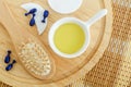 Small white bowl with cosmetic massage, cleansing oil, face serum capsules and wooden hairbrush. Natural haircare and spa