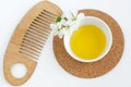 Small white bowl with cosmetic oil, white flowers and wooden hair brush. Natural spa and beauty treatment recipe. Top view Royalty Free Stock Photo