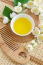 Small white bowl with cosmetic oil, white jasmine flowers and wooden hair brush. Natural spa and beauty treatment recipe. Top view Royalty Free Stock Photo