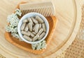Small white bowl with food supplement capsules, wooden hair brush and yarrow flowers. Natural healthcare, herbal medicine Royalty Free Stock Photo