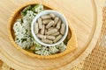 Small white bowl with food supplement capsules and yarrow flowers. Natural healthcare, herbal medicine, skincare and beauty Royalty Free Stock Photo