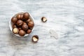 small white bowl with macadamia nuts, next to a nut opener and an open nut