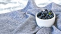 Small White Bowl of Organic Blueberries on Wooden Table with kitchen towel. Copy space. Summer fruit berries Royalty Free Stock Photo