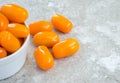 Small bowl overflowing with orange grape tomatoes on a gray marble background Royalty Free Stock Photo