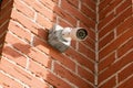 Small white CCTV camera on the corner of the facade of brick building Royalty Free Stock Photo