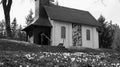 Small white chapel on hill behind white flowers in black and white Royalty Free Stock Photo