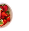 Small white china bowl filled with succulent juicy fresh red strawberries on a white background.Summer ripe berries.Delicious Royalty Free Stock Photo