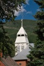 Small white church with a tall steeple and a cross on top, set in a rural landscape Royalty Free Stock Photo