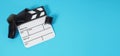 Small white clapper board and film roll on blue or turquoise background. It use in movie and video production Royalty Free Stock Photo