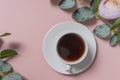 a small white coffee mug on a white saucer. espresso. flatlay. the view from the top. soft pink background with flowers. copyspace