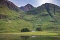 Small white cottage below magnificent mountains next to Loch Achtriochtan ,Glencoe,Scotland,UK Royalty Free Stock Photo