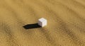A small white cube rests on a textured surface of fine brown pebbles. The surfac Royalty Free Stock Photo