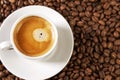 A small white cup of coffee stands on coffee beans. Fragrant pleasure. Background. Space for text. Close-up Royalty Free Stock Photo