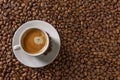 A small white cup of coffee stands on coffee beans. Fragrant pleasure. Background. Space for text. Top view Royalty Free Stock Photo