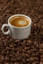 A small white cup of coffee stands on coffee beans. Fragrant pleasure. Background. Space for text. Royalty Free Stock Photo