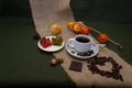 Small white cup with coffee, coffee beans coffee beans as hearts on burlap green background Royalty Free Stock Photo
