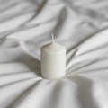 White cylindrical candle is placed upright on a white, slightly Royalty Free Stock Photo