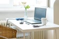 Small white desk at the window with a laptop as a workspace for studying or home office work, copy space Royalty Free Stock Photo