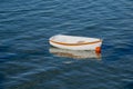 Small white dinghy with clinker lines and orange stripe