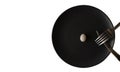 Small white egg on a black plate with a fork and knife on an isolated white background. Royalty Free Stock Photo