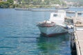 Small white fishing boat anchored next to the dock in town Royalty Free Stock Photo