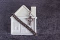 Small white house, chain and a decorative key on a dark backgrou