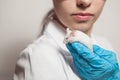 A small white mouse with red eyes in the hand of a scientist in a blue rubber glove.