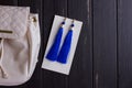 Small white leather woman`s backpack and blue earrings of thread Royalty Free Stock Photo