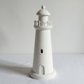 A small white lighthouse model made of a smooth material, possibly ceramic or Royalty Free Stock Photo