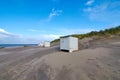 Small white locker house at the North Sea beach in the Netherlands near Texel. The blue sky is interspersed with clouds Royalty Free Stock Photo