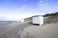 Small white locker house at the North Sea beach in the Netherlands. The blue sky is interspersed with clouds Royalty Free Stock Photo