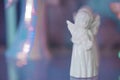 Small white marble figurine of an angel in dress on a pearlescent pink blue blurred bokeh background. Close-up Royalty Free Stock Photo