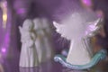 Small white marble figurine of an angel with fluffy wings on a light violet pink blurred bokeh background. Back view. Royalty Free Stock Photo