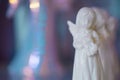 Small white marble figurine of an angel on a pearlescent pink blue blurred bokeh background. Royalty Free Stock Photo