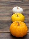 Small white, medium yellow, and big orange pumpkins put vertically on dark wooden background Royalty Free Stock Photo