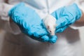 A small white mouse with red eyes in the hand of a scientist in a blue rubber glove.