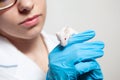 A small white mouse with red eyes in the hand of a scientist in a blue rubber glove.