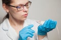 A small white mouse with red eyes in the hand of a scientist in a blue rubber glove.