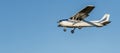 Small white plane with blue stripes of a cessna propeller flying from side view point of view in a clear blue cloudless sky before Royalty Free Stock Photo