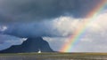 Small white sailboat and beautiful rainbow over amazing Le Morne mountain peak in Mauritius island. Royalty Free Stock Photo