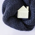 Small white toy house lies on a warm cozy scarf. Concept-insula Royalty Free Stock Photo