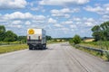 A small white truck with a tail lift and a big smile goes on the highway between cities