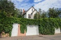 Small white two-storied residential house, fence with hops